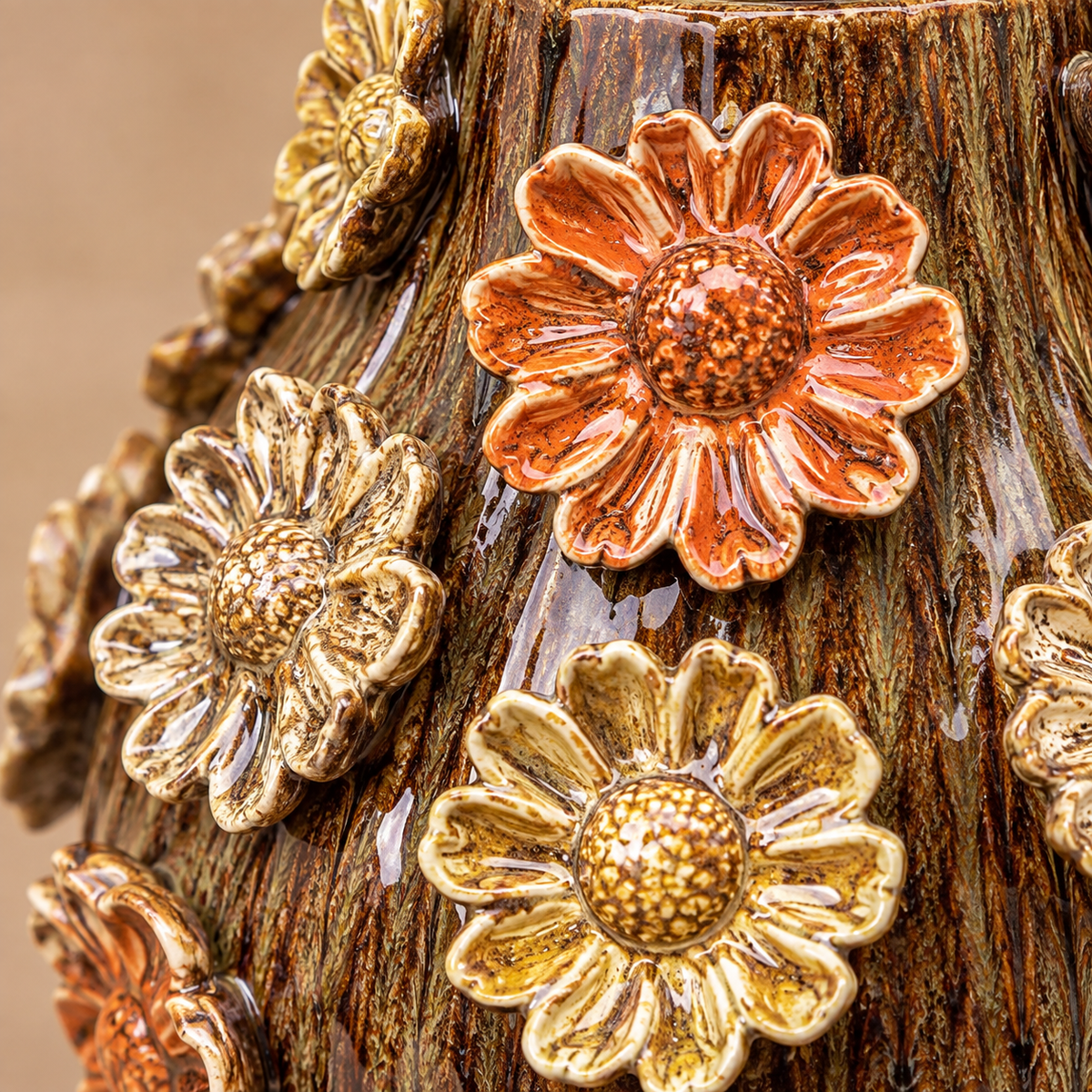 Close-up of brown glazed ceramic vase with raised orange, gold and cream 3D floral details