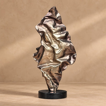 Front view of a contemporary abstract metal sculpture with a textured metallic finish mounted on a black marble base.