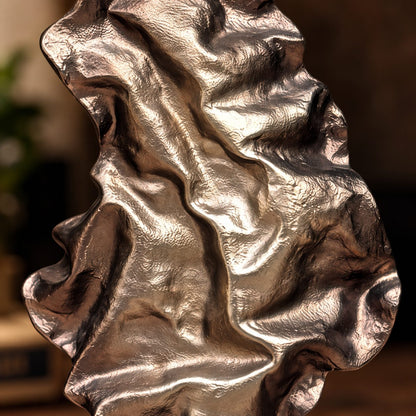 Close-up showing the handcrafted textured metallic finish of a contemporary abstract decorative sculpture.