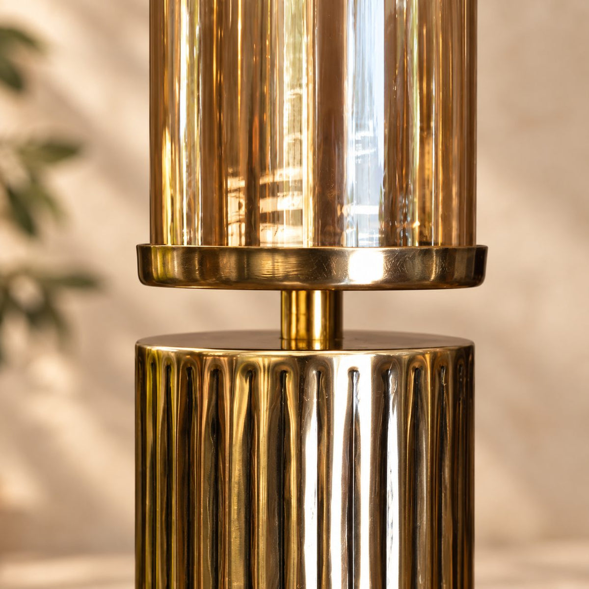 Close-up view of the amber glass hurricane candle holder highlighting the premium ribbed gold metal base and handcrafted finish.
