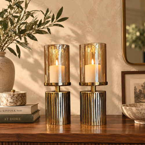 Luxury amber glass hurricane candle holder set with lit pillar candles styled on a walnut console table, featuring a ribbed gold metal base for elegant home décor.