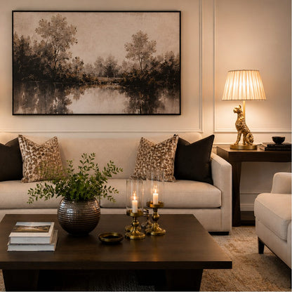 Luxury antique brass leopard table lamp with a pleated fabric shade styled on a wooden side table in an elegant living room featuring a beige sofa, modern wall art, and warm ambient lighting by Inara Home Decor.