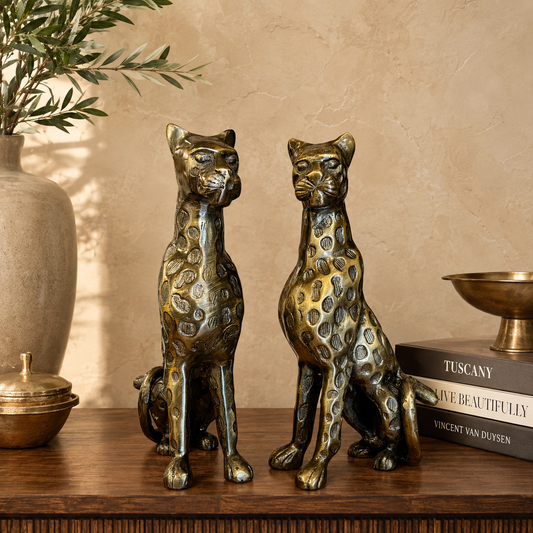 Luxury bronze leopard pair sculptures styled on a premium wooden tabletop against a warm beige Venetian plaster wall, creating an elegant luxury home décor setting by Inara Home Decor.