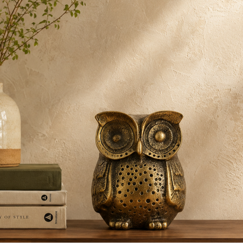 Antique brass owl figurine styled on a wooden console table with books and ceramic vase in a modern luxury home.