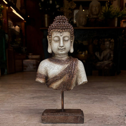A serene Buddha bust sculpture with an antique sandstone finish, mounted on a dark metallic rod and rectangular base.