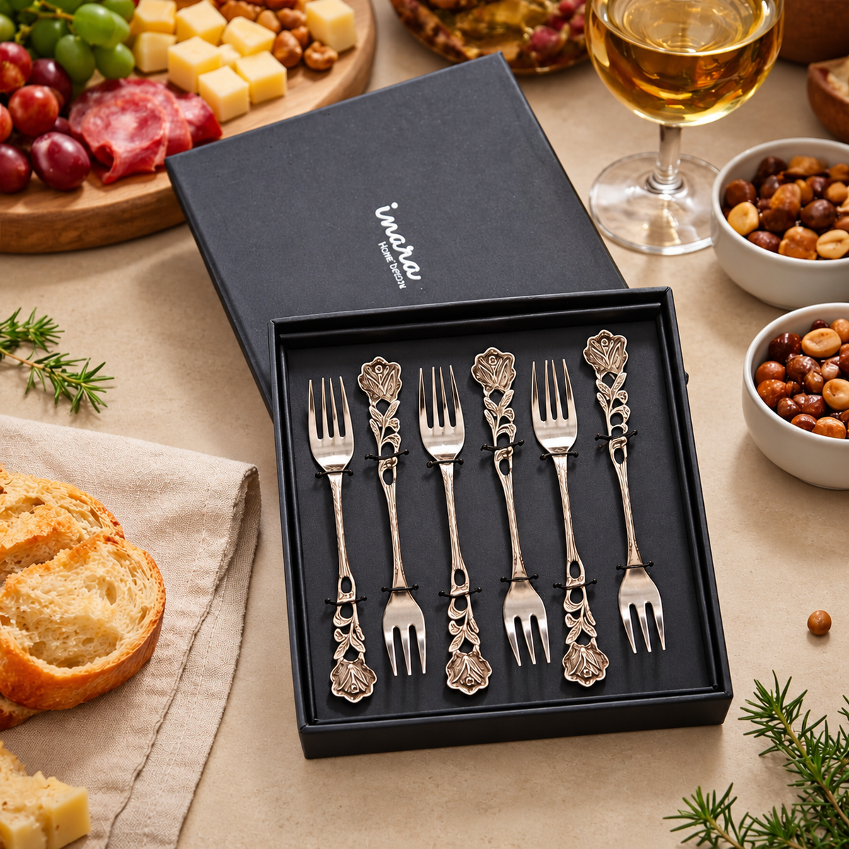Antique Rose Dessert Forks Set of 6 in a premium gift box displayed on a warm beige Venetian seamless matte microcement surface with gourmet food and wine, luxury stainless steel servingware by Inara Home Decor.