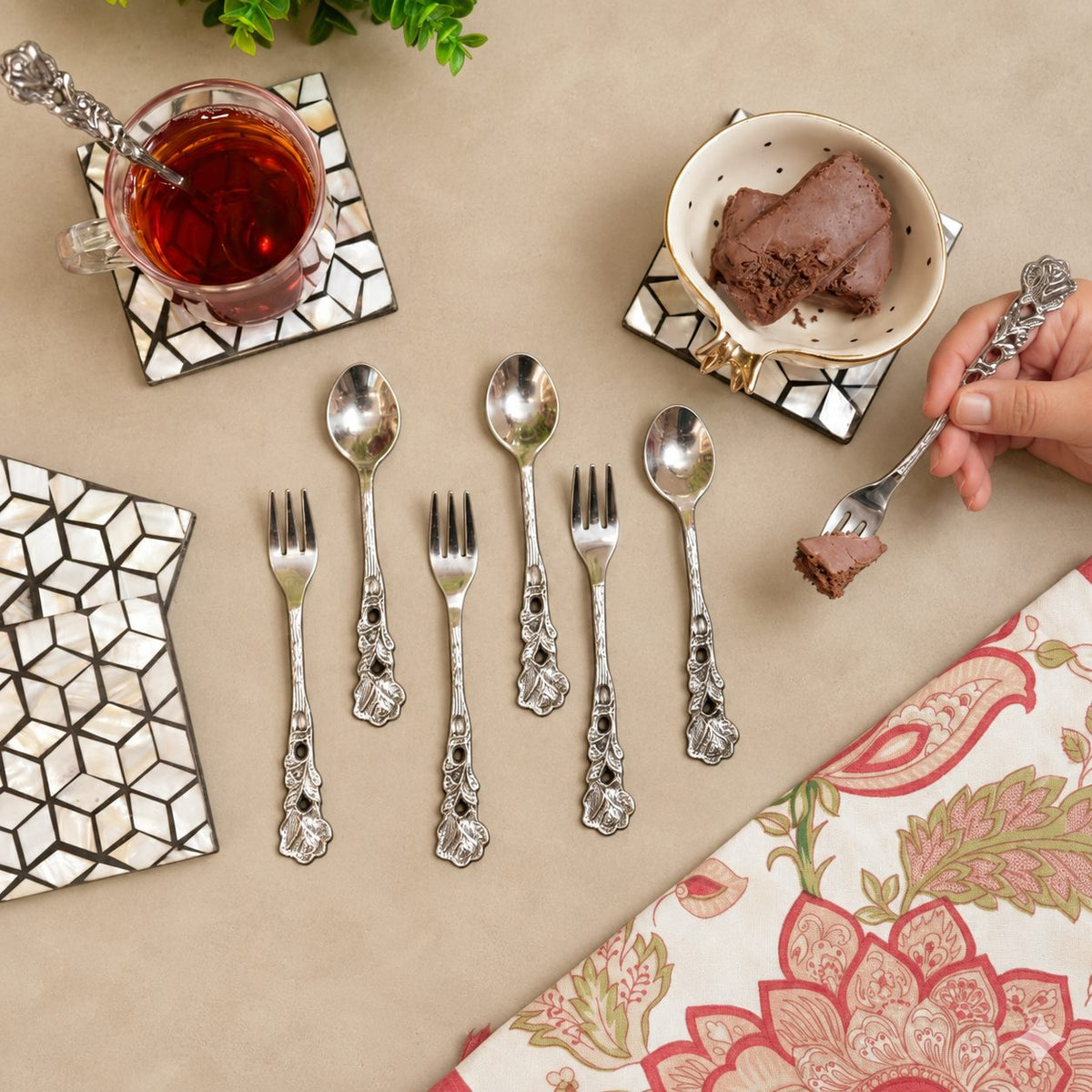 Antique Rose dessert spoons and forks set arranged with tea and chocolate dessert on a warm beige Venetian seamless matte microcement tabletop, luxury vintage servingware by Inara Home Decor.