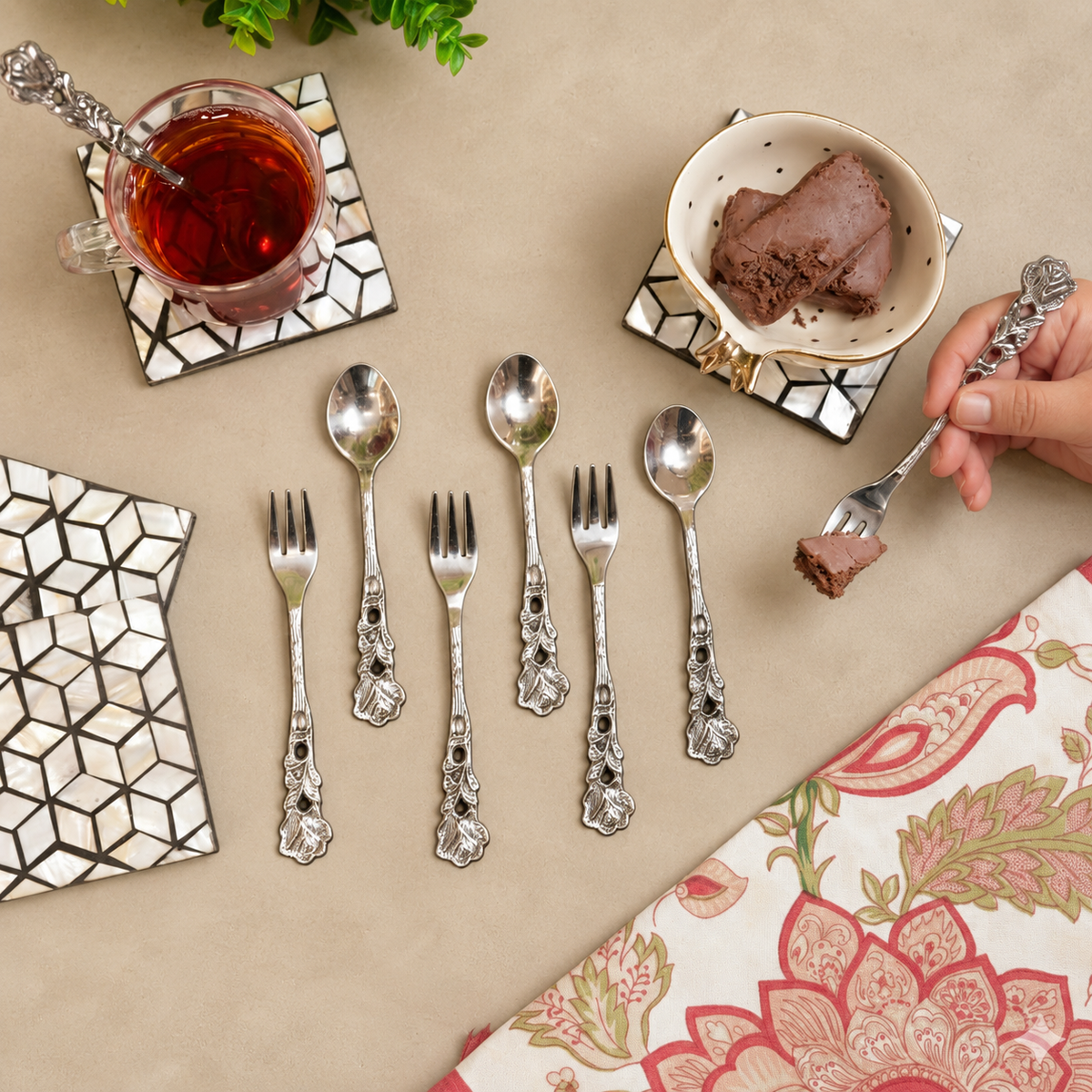 Antique Rose dessert spoons and forks set arranged with tea and chocolate dessert on a warm beige Venetian seamless matte microcement tabletop, luxury vintage servingware by Inara Home Decor.