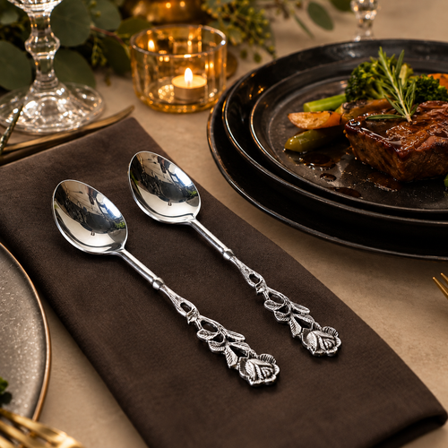 Antique Rose Silver Dessert Spoons Set of 2 displayed on a dark linen napkin with a luxury dining table setting on a warm beige Venetian seamless matte microcement surface.