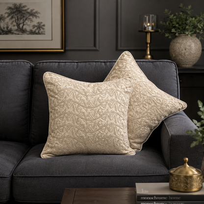 Beige embroidered cushion cover with intricate wave pattern styling on a dark grey sofa in a modern luxury living room.