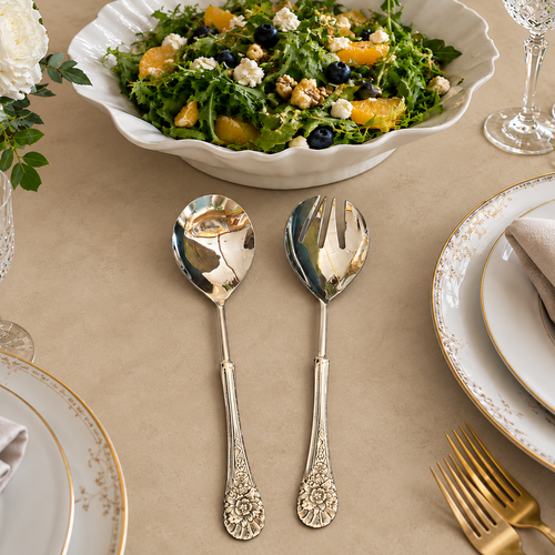 Antique silver floral salad serving spoon and fork set styled on a warm beige Venetian seamless matte microcement table beside a fresh salad bowl, luxury tableware for elegant dining and entertaining.