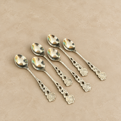 Antique silver floral tea spoons set of 6 with ornate vintage handles, premium stainless steel dessert and coffee spoons displayed on a warm beige Venetian matte microcement surface, luxury tableware by Inara Home Decor.