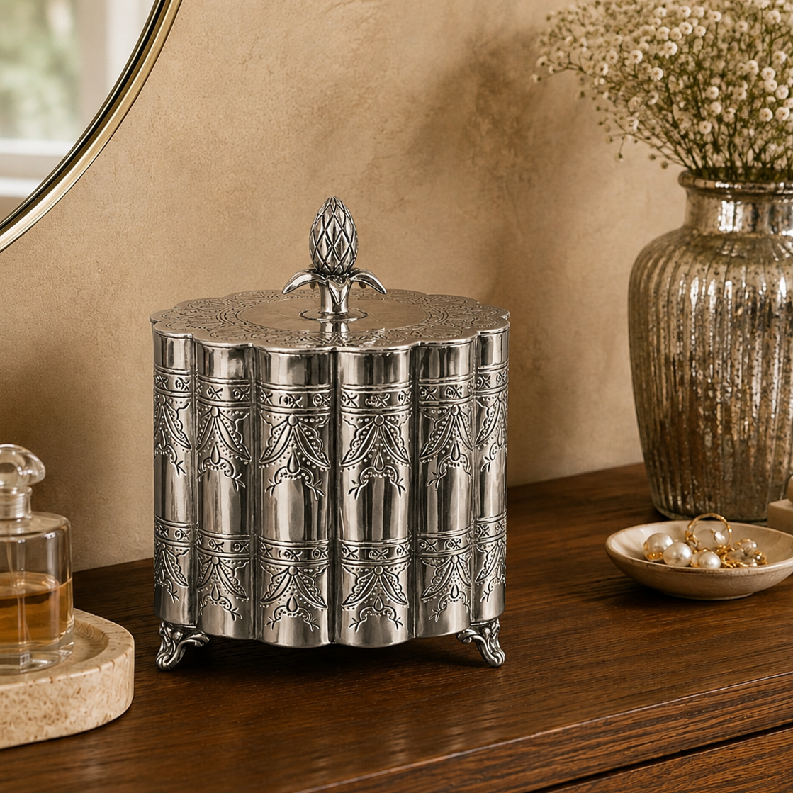Antique silver ornate decorative storage box with engraved detailing displayed on a wooden console table alongside an antique silver vase, creating a luxury home décor lifestyle setting.