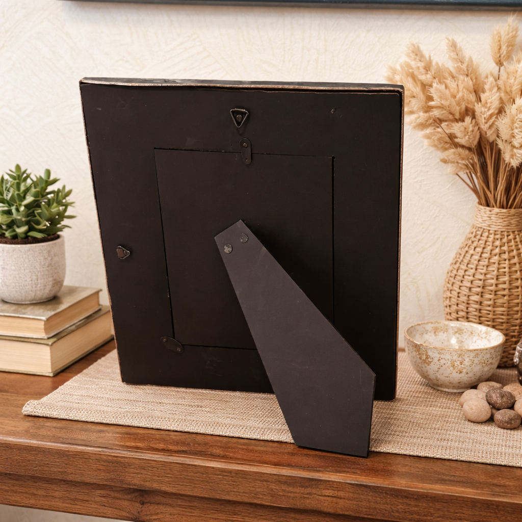 Back view of an antique silver handcrafted photo frame with sturdy tabletop stand, styled on a wooden console with neutral décor accents in a luxury home setting.