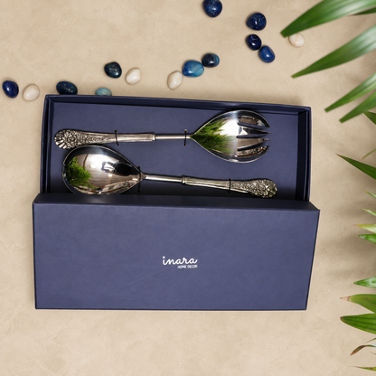Antique silver salad serving spoon and fork set in a premium Inara Home Decor gift box on a warm beige Venetian seamless matte microcement surface, featuring ornate floral handles and elegant flat lay styling.