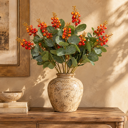 Artificial berry eucalyptus stems displayed in a rustic ceramic vase on a wooden console table for elegant home décor.
