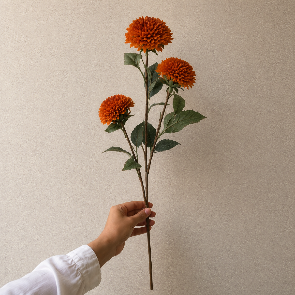 Single artificial orange dahlia stem with realistic layered petals and lifelike green foliage, perfect for elegant floral arrangements and home décor.