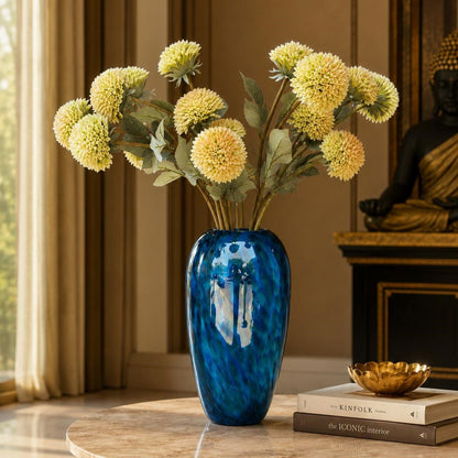 Artificial white dahlia stems arranged in a blue glass vase on a luxury living room table, creating an elegant and timeless home décor display.