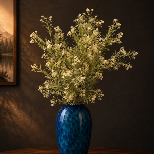 Artificial white wildflower stems beautifully arranged in a blue glass vase, adding timeless elegance to modern home interiors.