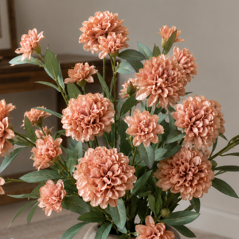Close-up detail view of artificial peach dahlia flower stems in a textured vase, showcasing layered petals and realistic foliage against a soft neutral background.