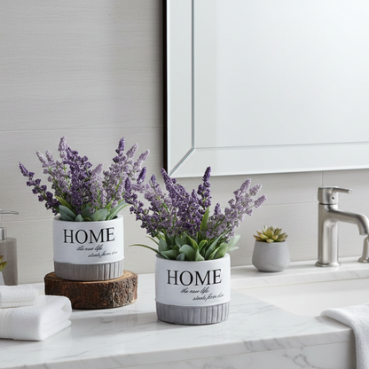 Artificial lavender flowering plants in decorative ceramic pots styled on a bathroom vanity for elegant and maintenance-free décor.