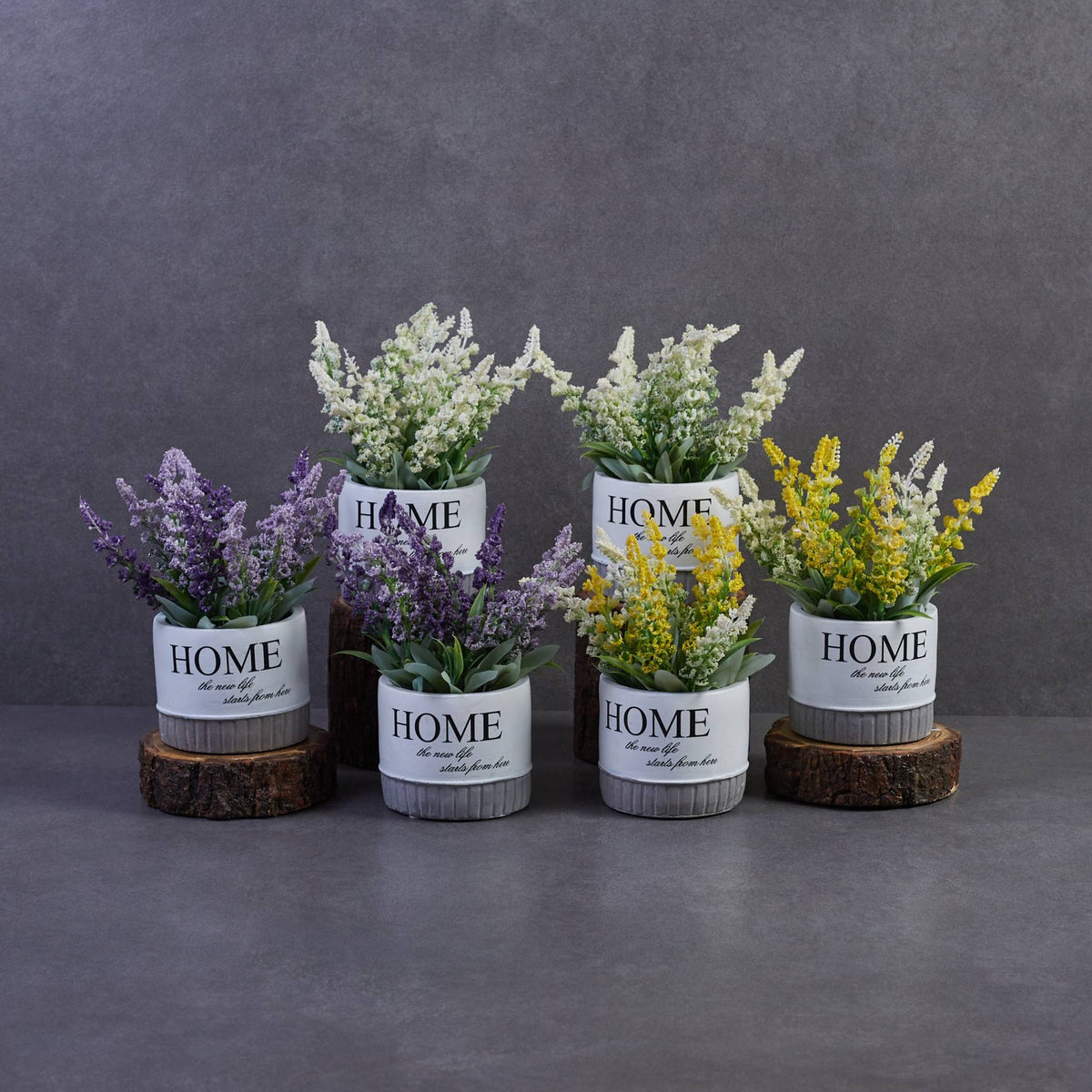 Artificial flowering plants in ceramic pots with lavender, white, and yellow blooms arranged together for stylish indoor home decoration.