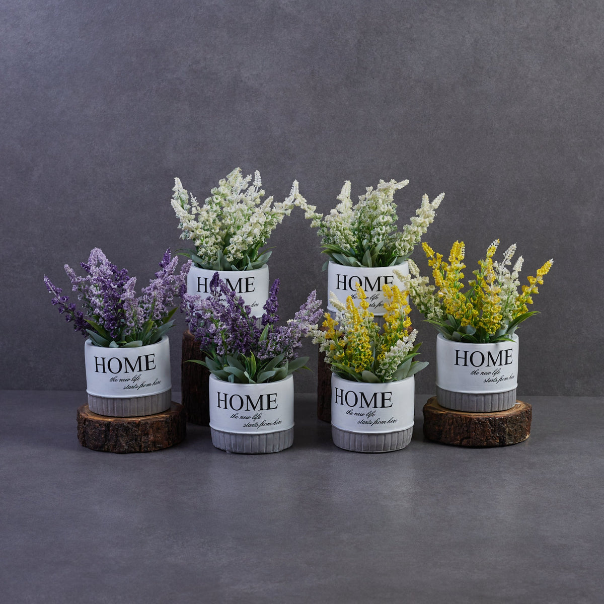 Artificial flowering plants in ceramic pots with lavender, white, and yellow blooms arranged together for stylish indoor home decoration.