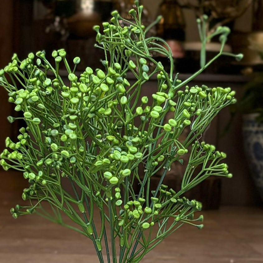 Close-up of realistic artificial green baby's breath filler stem with lifelike buds and detailed foliage.