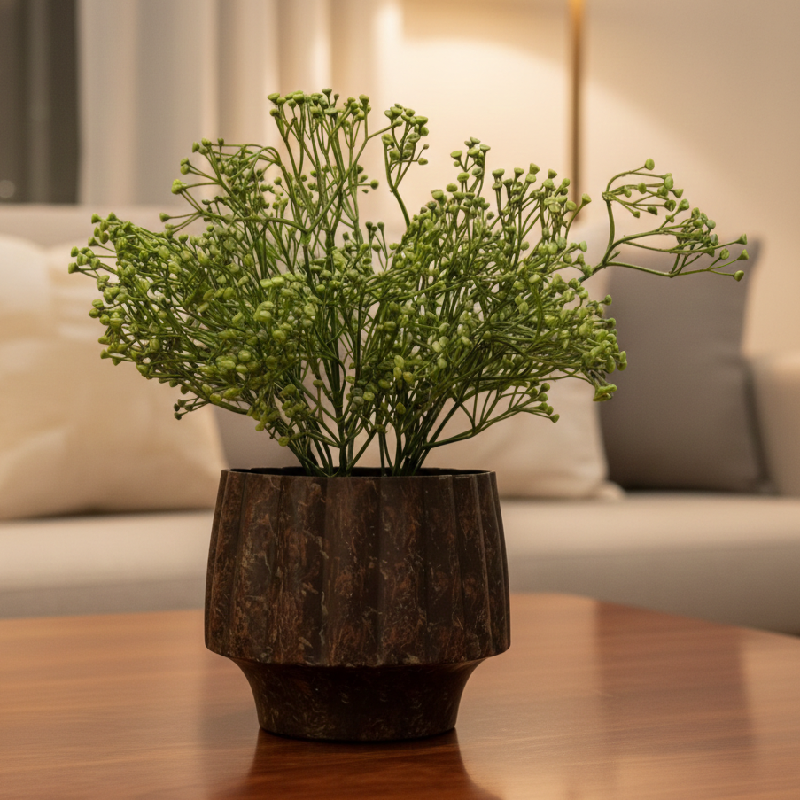 Artificial green baby's breath stem arranged in a modern decorative planter on a wooden coffee table.
