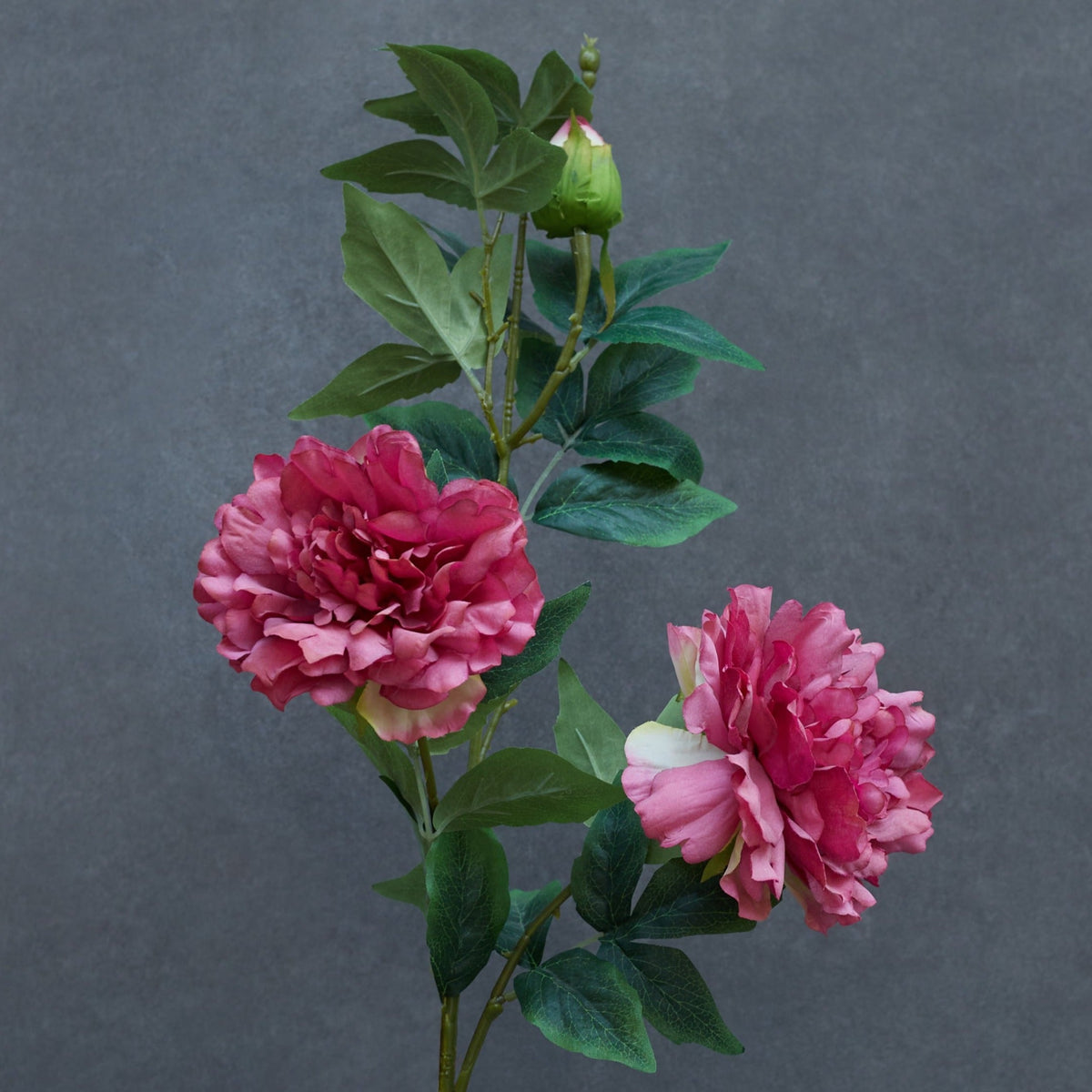 Artificial pink peony flower stem with two realistic blooms and one bud, crafted from premium silk and PU for home décor.