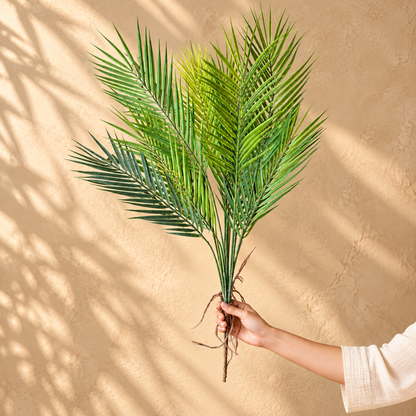 Artificial Palm Foliage Bunch with realistic green palm leaves, shown in hand to demonstrate the full 15-inch size.