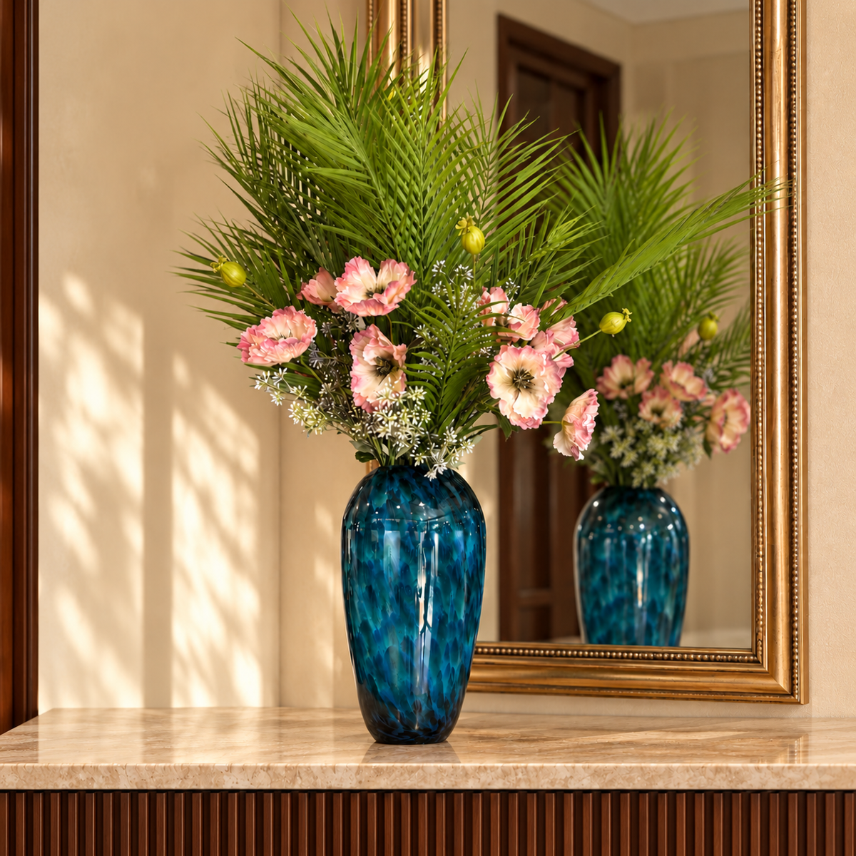 Artificial Palm Foliage Bunch arranged in a blue glass vase on a marble console table with a gold-framed mirror, creating an elegant tropical luxury home décor display.
