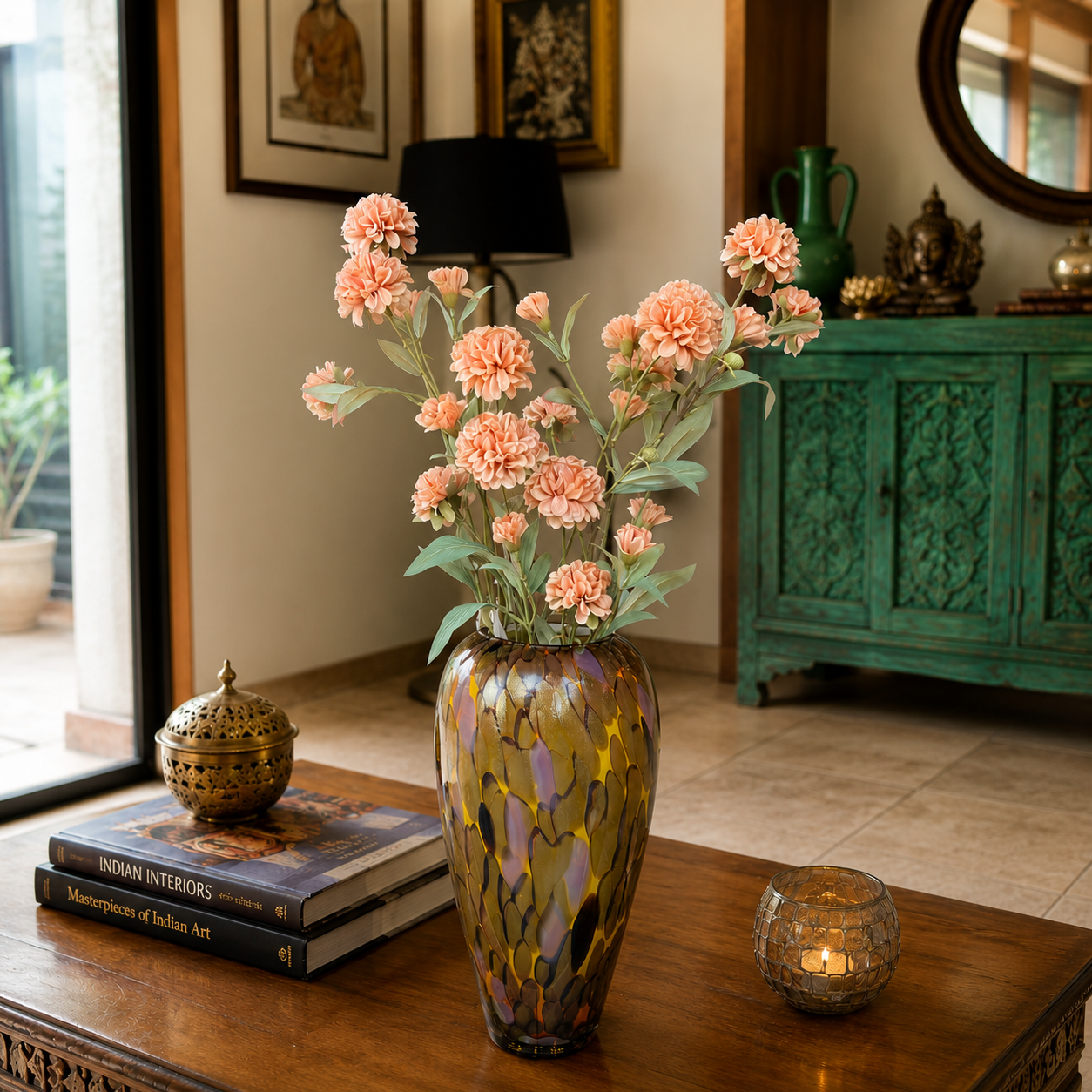Artificial peach carnation stems arranged in an amber glass vase on a wooden coffee table in a warm, elegant living room setting with decorative accents and natural light.