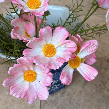 Close-up of real-touch artificial pink cosmos flowers with soft white petals and vibrant yellow centers.