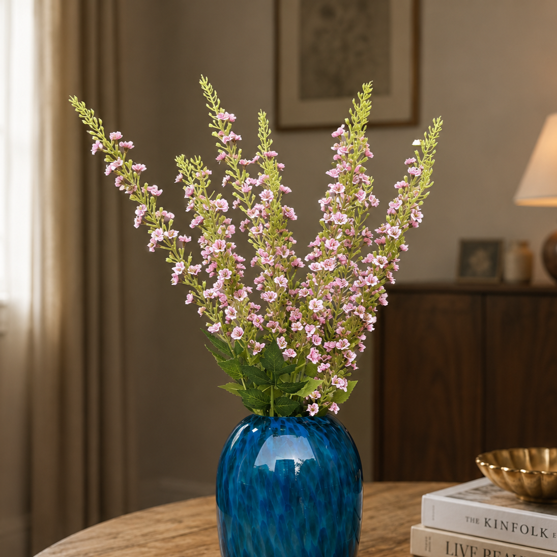 Artificial pink lavender flower stems arranged in a blue glass vase, creating an elegant luxury home décor display for living rooms, dining tables, and entryway styling.