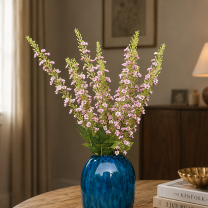 Artificial pink lavender flower stems arranged in a blue glass vase, creating an elegant luxury home décor display for living rooms, dining tables, and entryway styling.