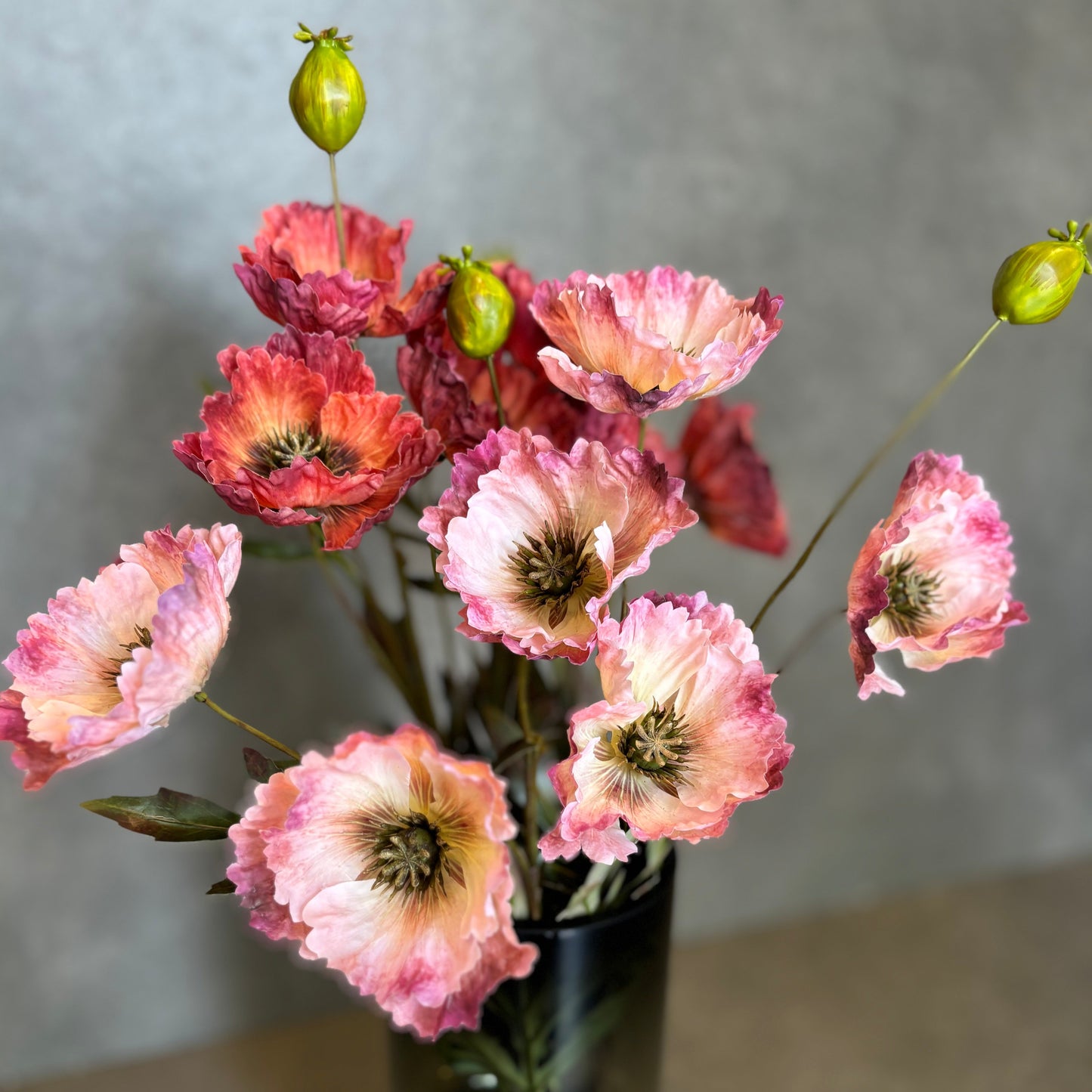 Close-up of Artificial Poppy Red flower stems with realistic petals and buds arranged in a vase.