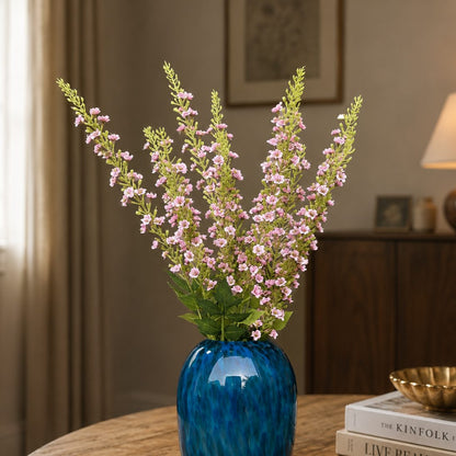 Artificial pink lavender flower stems arranged in a blue glass vase, creating an elegant luxury home décor display for living rooms, dining tables, and entryway styling.
