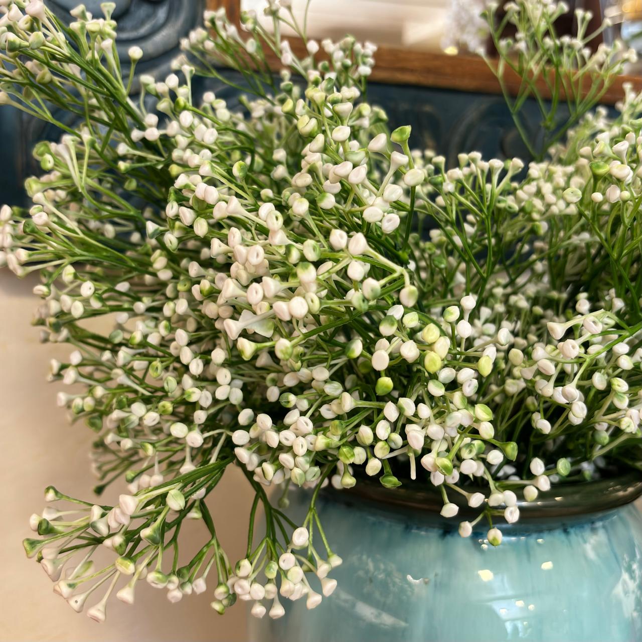 Close-up of artificial white berry buds stems arranged in a glazed ceramic vase, showcasing realistic botanical details and elegant home décor styling.