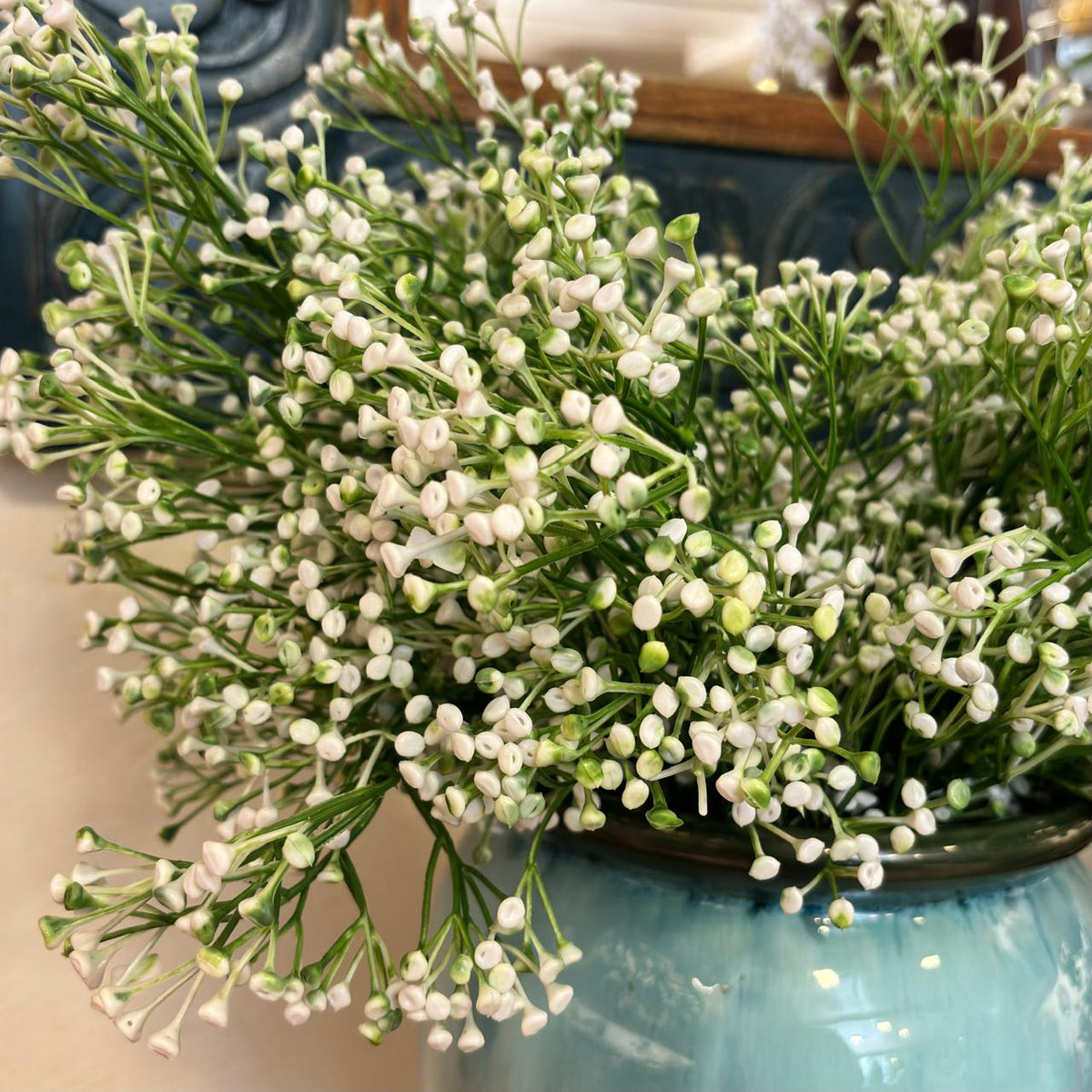 Close-up of artificial white berry buds stems arranged in a glazed ceramic vase, showcasing realistic botanical details and elegant home décor styling.