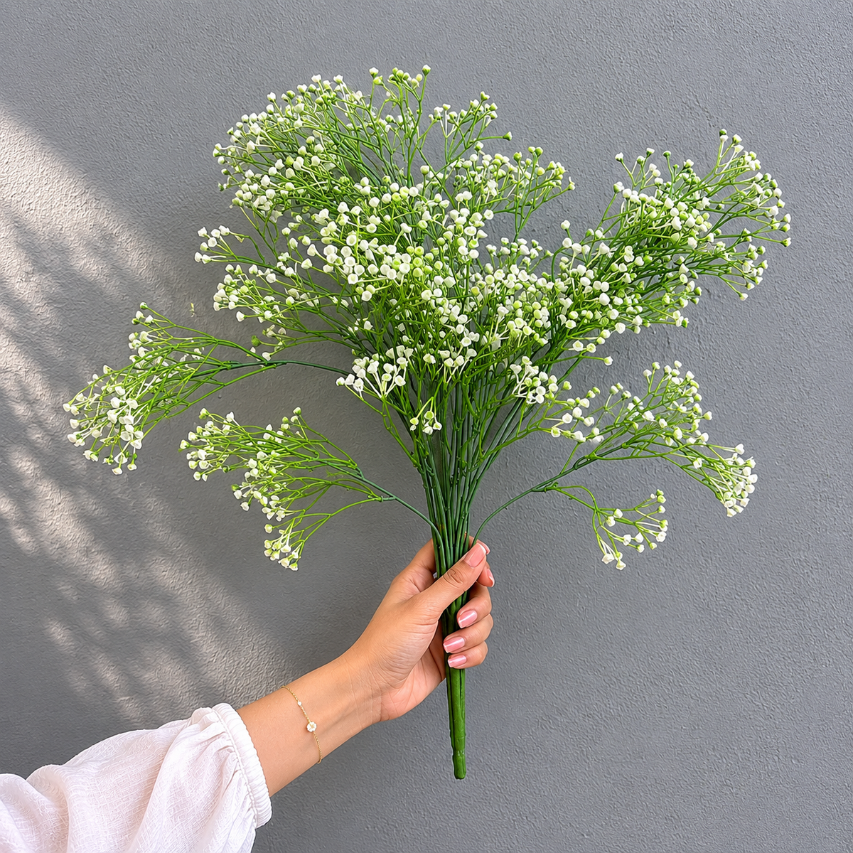 Hand holding a realistic Artificial White Berry Beads Bunch, showcasing its size, lifelike white berries, and green stems for elegant floral arrangements.