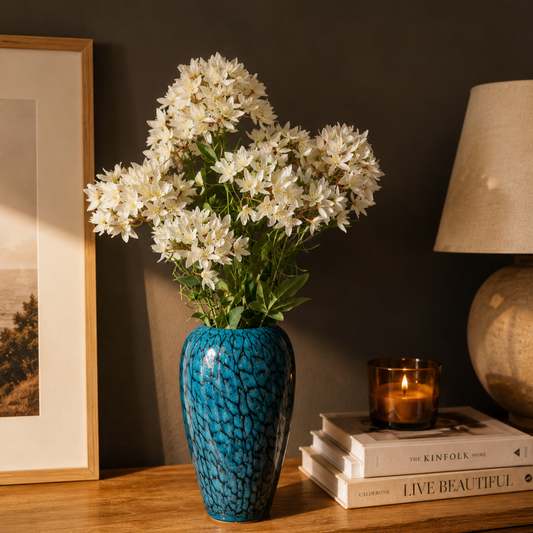 Artificial White Star Cluster Stem arranged in a blue ceramic vase on a wooden console table, creating an elegant and timeless home décor display.