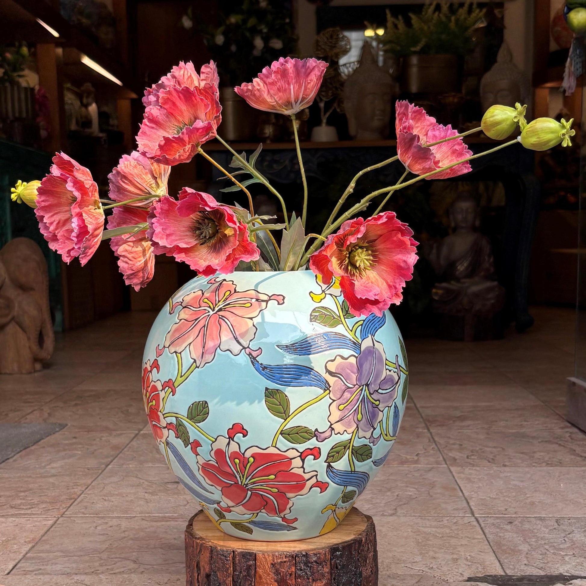 Close-up of a handcrafted ceramic jar with intricate floral artwork and red poppy flowers in an elegant indoor setting.