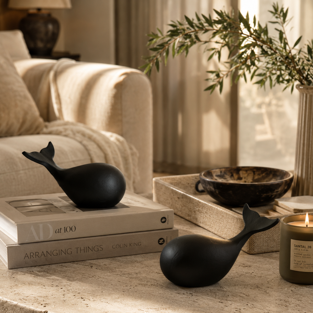 Minimalist black whale sculpture set styled on a luxury coffee table with books and candle in a modern living room.