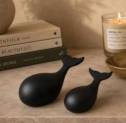 Elegant black whale sculpture set styled on a modern console table with books, candle, and decorative accessories.