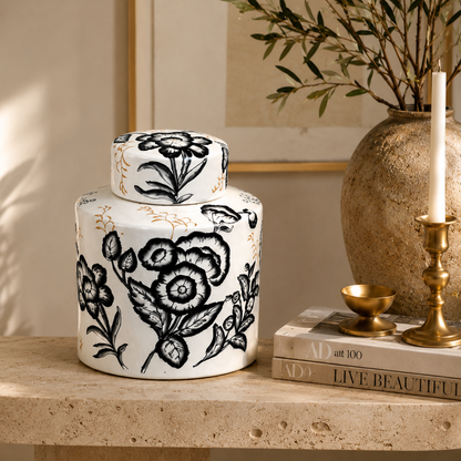 Hand-painted black and white ceramic ginger jar styled on a travertine console table with books and brass décor for elegant living room styling.