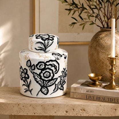 Hand-painted black and white ceramic ginger jar styled on a travertine console table with books and brass décor for elegant living room styling.