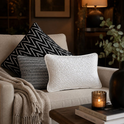 Black and white designer cushion cover set styled on a beige sofa in a luxury living room, featuring geometric patterns and elegant embroidered detailing for modern home décor by Inara Home Decor.