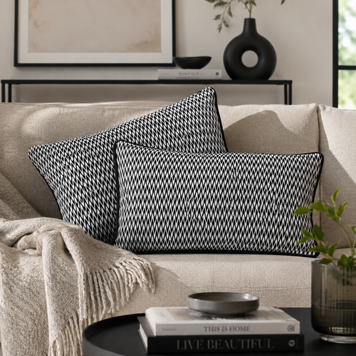 Black and white geometric velvet cushion covers styled on a beige sofa in a modern living room, adding contemporary elegance and luxury home decor appeal.