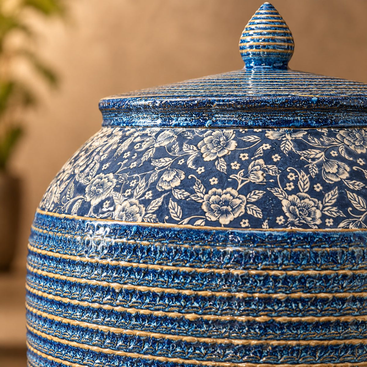 Close-up of a handcrafted blue floral ceramic decorative storage jar showcasing intricate floral detailing and textured glazed finish.